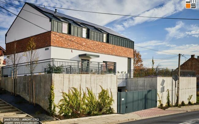 Nowoczesny projekt indywidualny domu jednorodzinnego to połączenie eleganckich ponadczasowych materiałów elewacyjnych jak cegła, czarne aluminium i beton architektoniczny