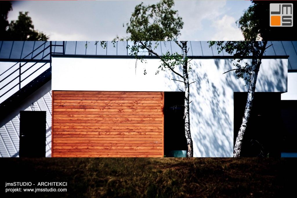w nowoczesnym projekcie domu zestawiono ze sobą drewno elewacyjne szarą blachę i biały tynk tworząc designerski dom