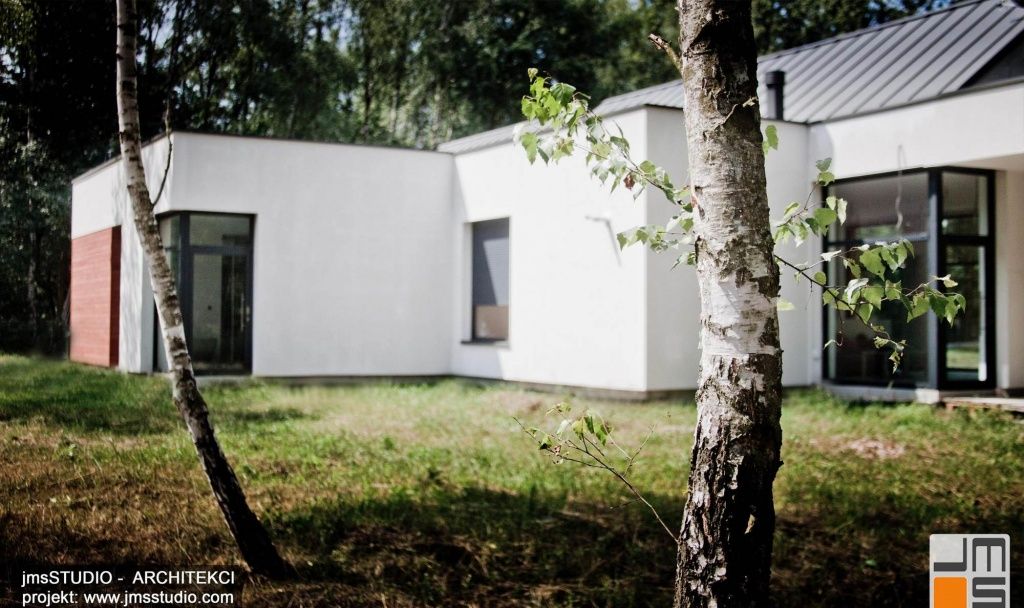 projekt nowoczesnego domu z dużymi przeszkleniami i drewnem na elewacji zakładał jego dobre wkomponowanie w teren z drzewami pod Brzeskiem